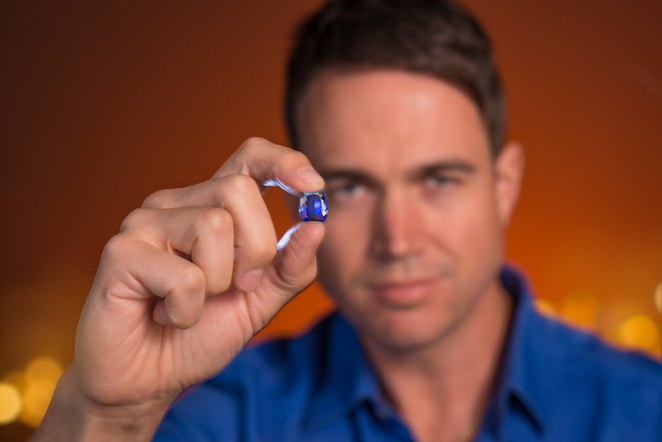 Josh Mulrine, rare gemstone hunter at Vivid Jewels in Canberra, holding a blue sapphire