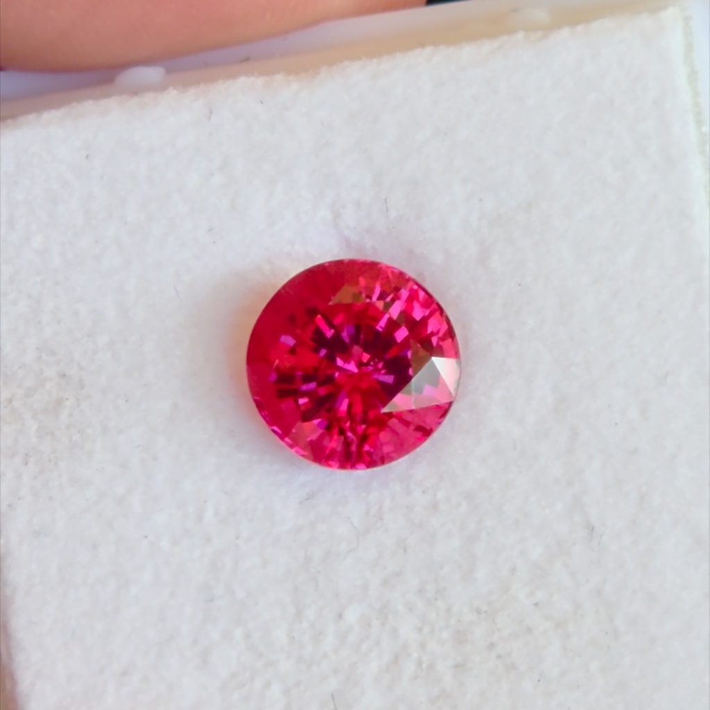 3.58 carat pinkish red Jedi spinel from Mogok, Burma, on a white gem pad