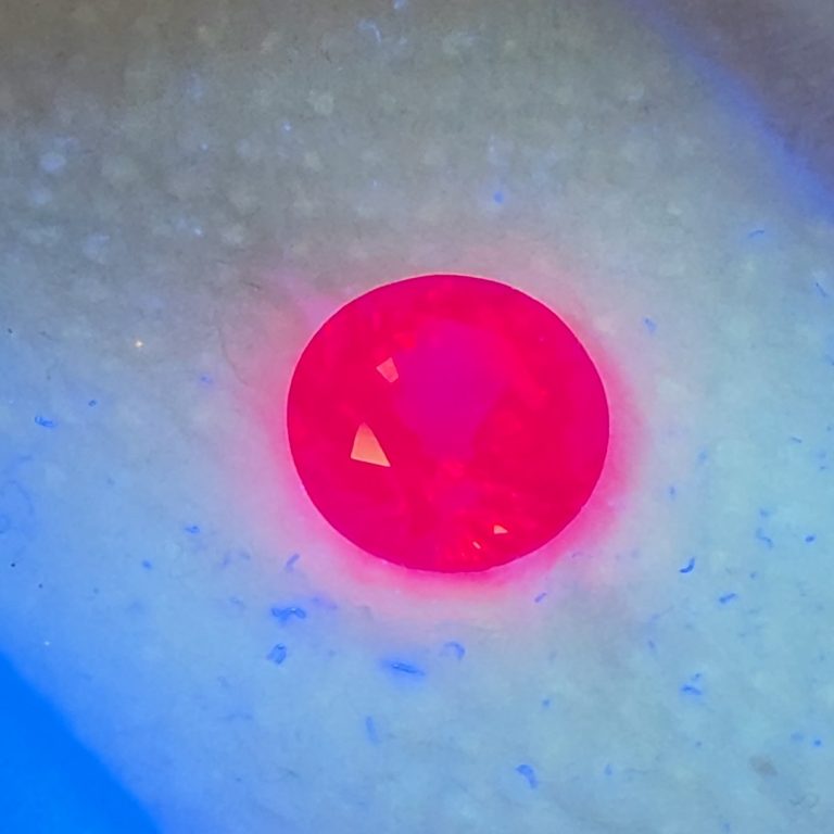 Close-up of the neon Jedi spinel glowing red under UV light
