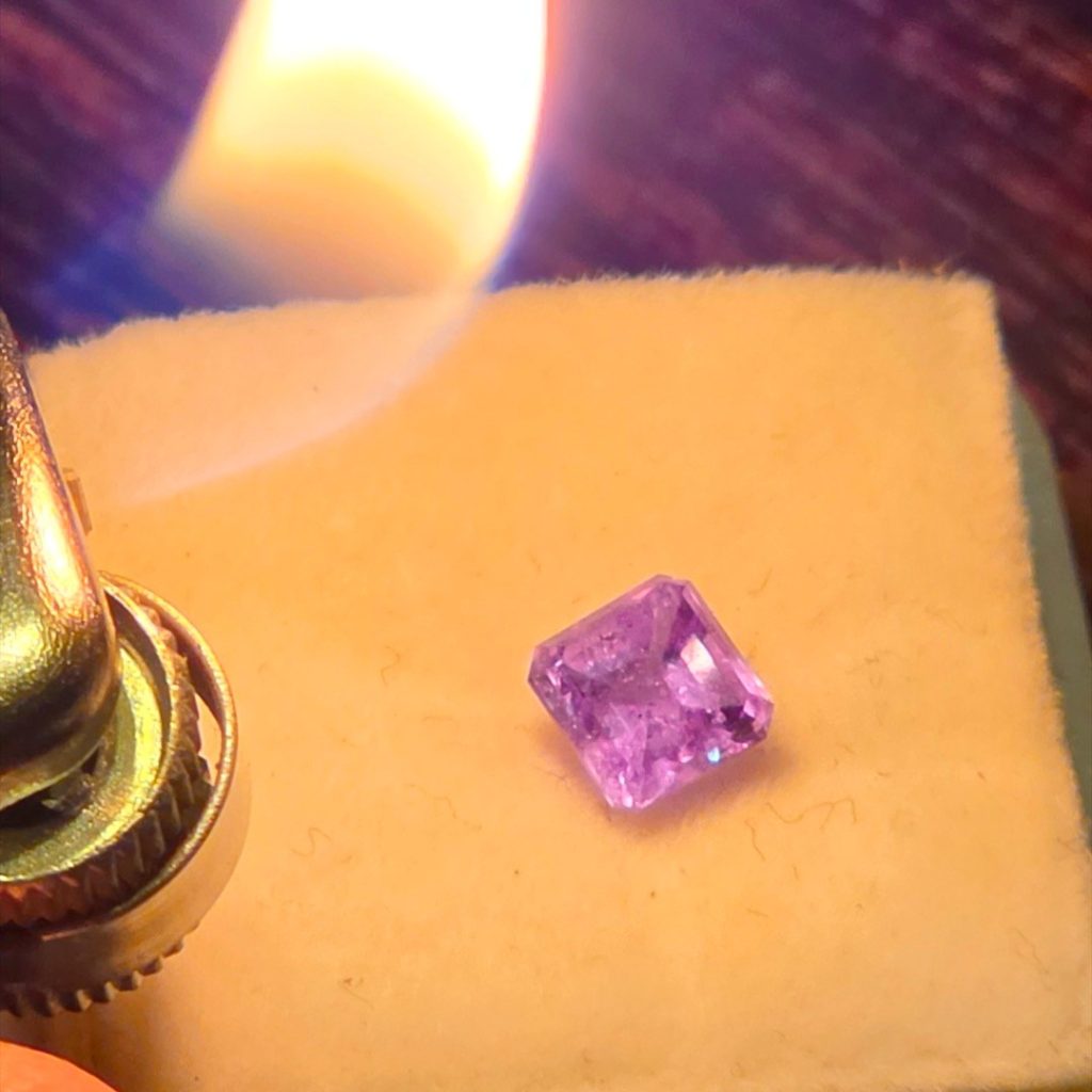 0.94ct Russian alexandrite turning pinkish-purple by candlelight on a gem pad