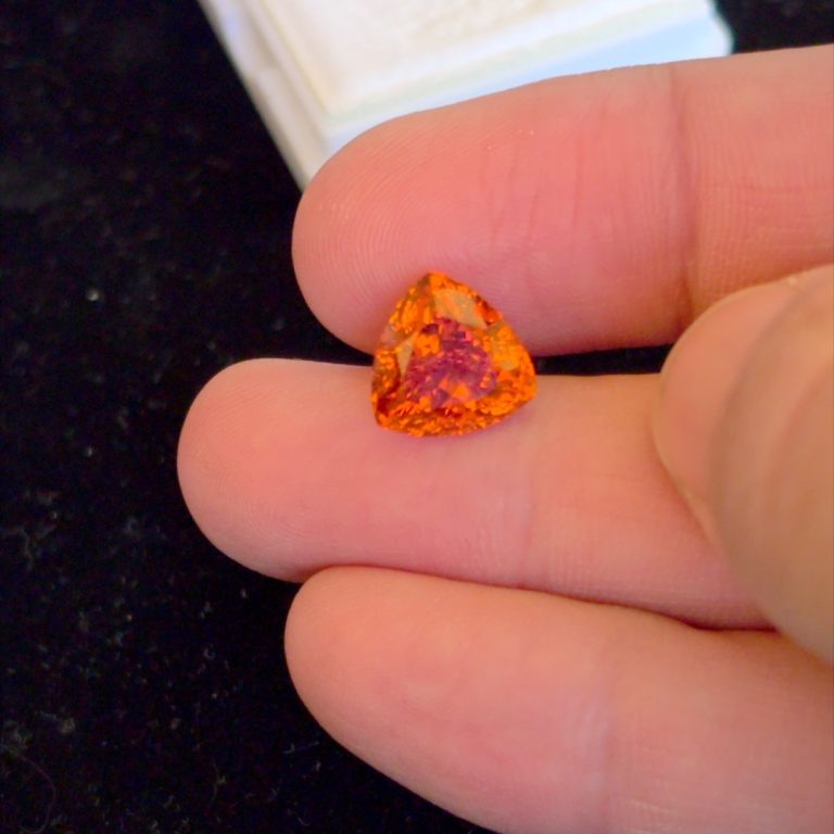 A 7 carat vivid orange spessartite garnet held between the fingers