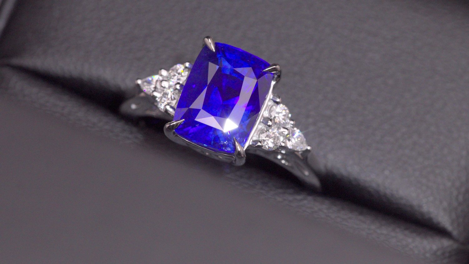 5.6 carat vivid royal blue Ceylon sapphire engagement ring with a trio of white diamonds on each shoulder